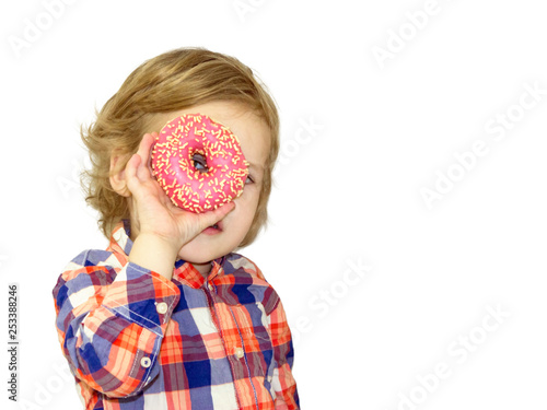 Little happy cute boy is eating donut on white background wall. Child is having fun with donut. Tasty food for playing kids. Funny time  with sweet food. Bright baby boy in a plaid shirt.