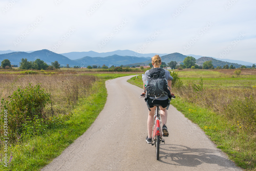 woman riding the bike through the fields in central croatia