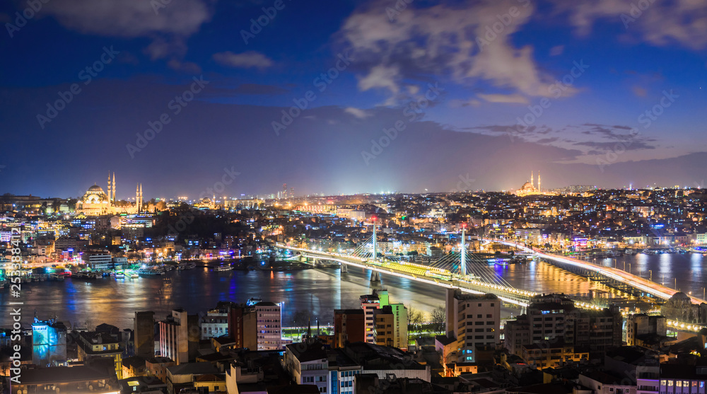 Panoramic view of Bosphorus with lots of illuminated bridges and mosques. Istanbul cityscape at night with cloudy sky. Touristic famous place of Turkey