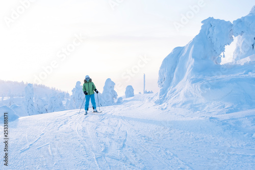 Skier on a snow-covered slope in The sunrise.  Morning in Lapland.