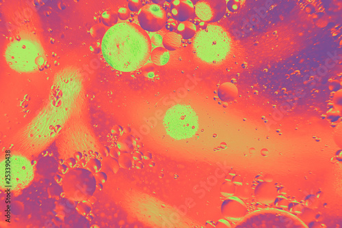 Abstract macro photography. Abstract background. Orange with purple color. Distortions in water with drops of oil. Bright abstraction, ultraviolet. Circles on the water