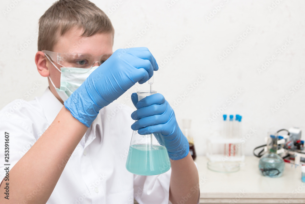 Science school, Medicine. A teenager boy conduct chemical experiments with tubes. On the table is a robot. STEM and STEAM education. Science and technology. Chemistry lab. Science school, Medicine. A teenager boy conduct chemical experiments with tubes. On the table is a robot. STEM and STEAM education. Science and technology. Chemistry lab.
