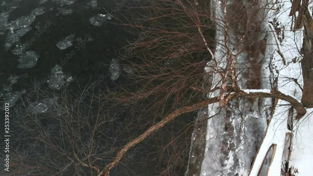 Tree Hanging Over Snowy River Bank by Icy Water AERIAL FLY UP Tree Hanging Over Snowy River Bank by Icy Water AERIAL FLY UP
