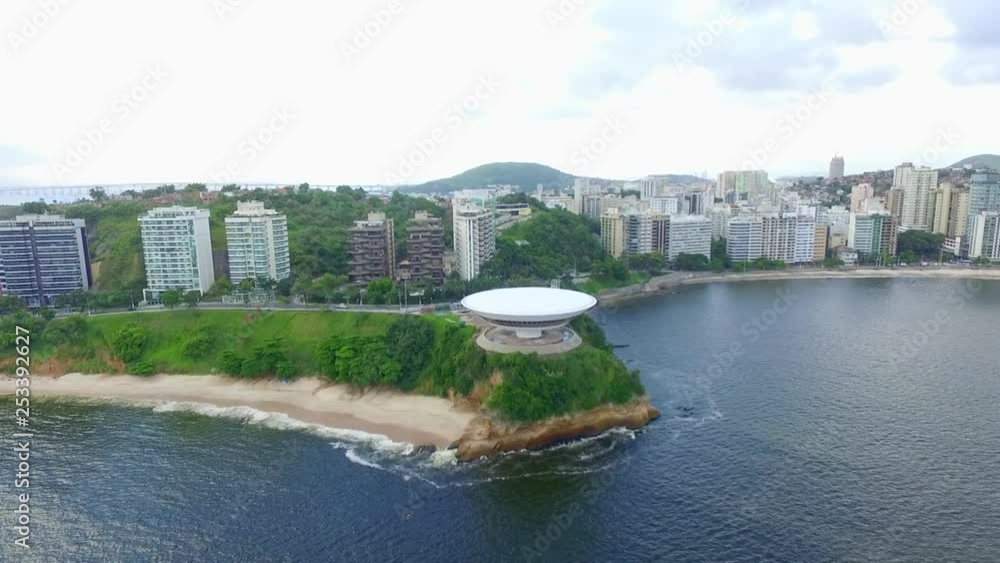 Drone panning the camera at Rio de Janeiro, near the beach, with buildings, an island, cars passing by and pedrestians wandering - summer season beautiful landscape. Drone panning the camera at Rio de Janeiro, near the beach, with buildings, an island, cars passing by and pedrestians wandering - summer season beautiful landscape.