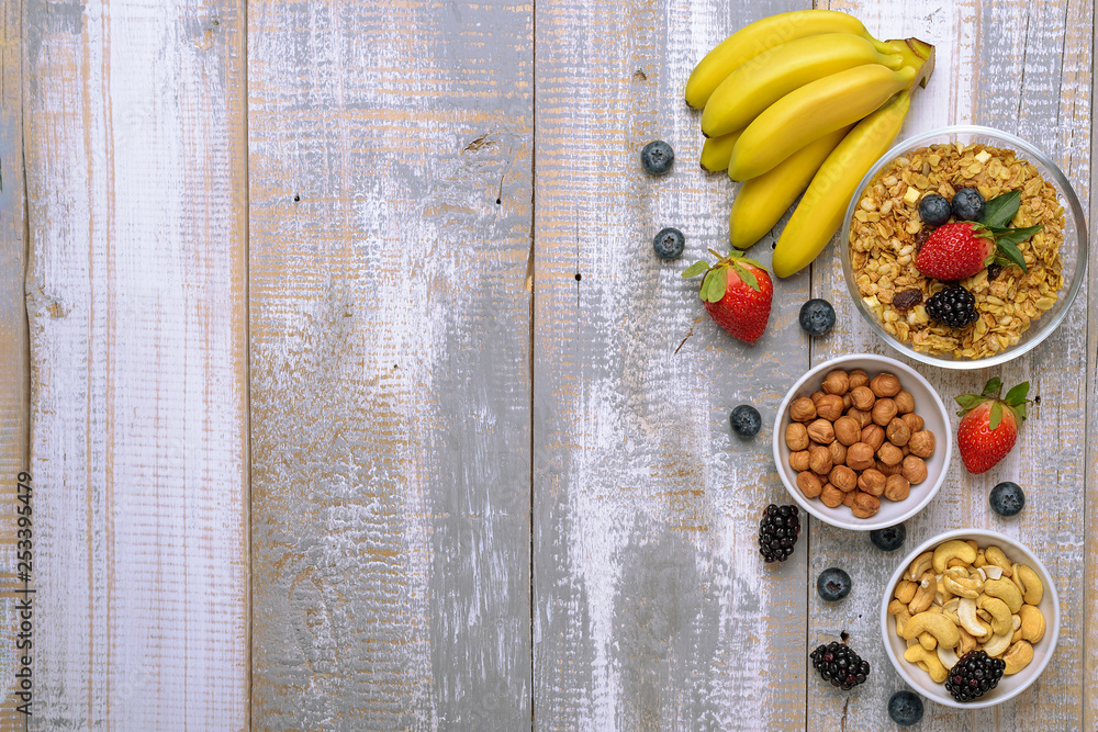 muesli with fruit, berries, nuts on wooden background