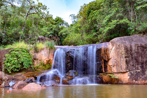 Waterfall in rain forest of Moeda in Minas Gerais state on cloudy day among rocks and vegetation