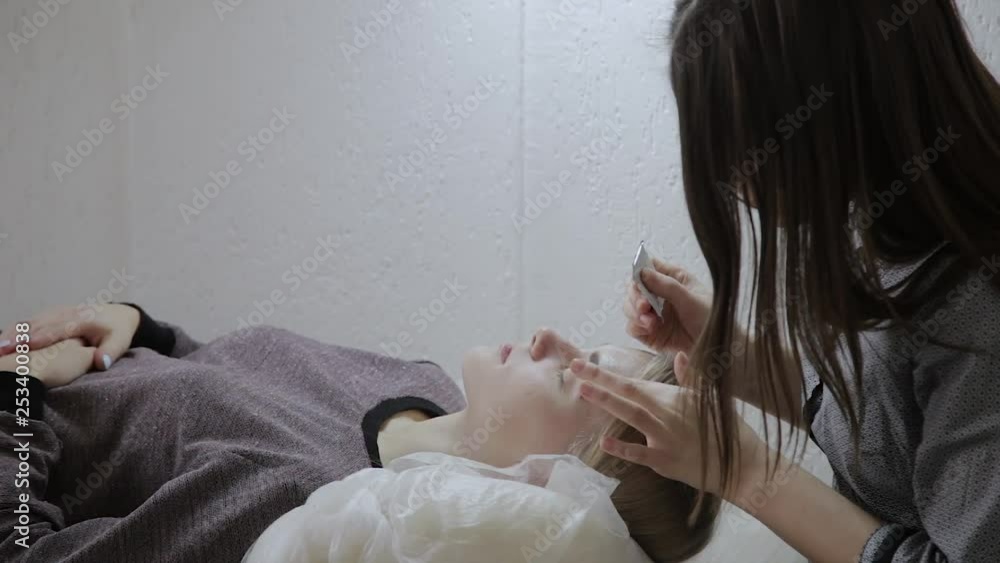 Masseur applies facial massage cream to a young girl in a beauty salon. Masseur applies facial massage cream to a young girl in a beauty salon.