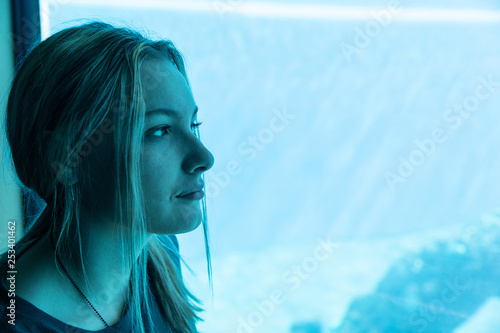 Teenage girl looking through glass at aquarium
