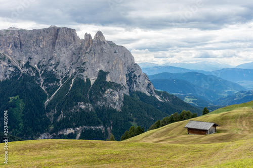 Italy, Alpe di Siusi, Seiser Alm with Sassolungo Langkofel Dolomite, an old barn in a field