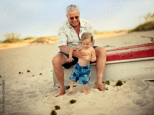 Grandfather holding grandson on beach