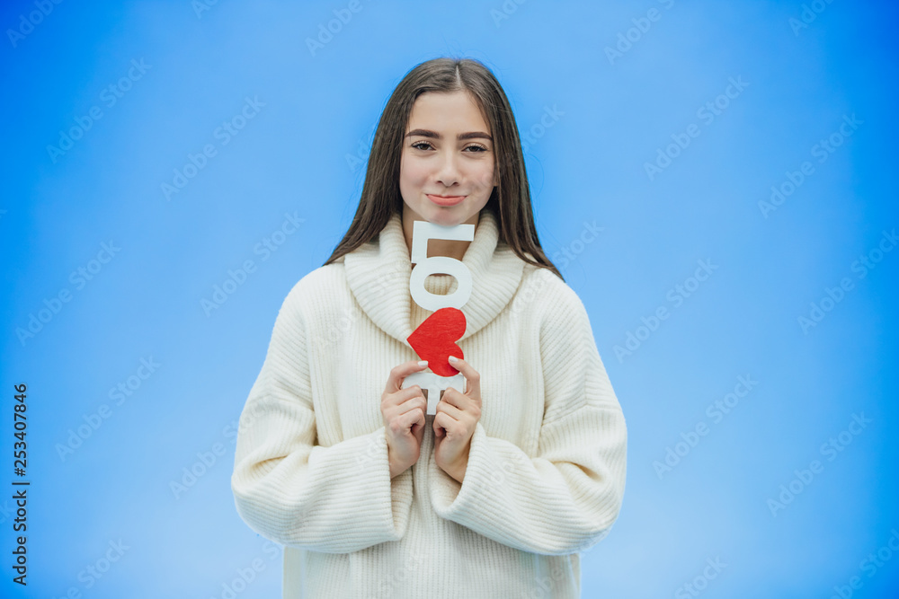 Young pretty girl dressed in white clothes. During this time it stands on a blue background. Holds a word of love in hands. Young pretty girl dressed in white clothes. During this time it stands on a blue background. Holds a word of love in hands.