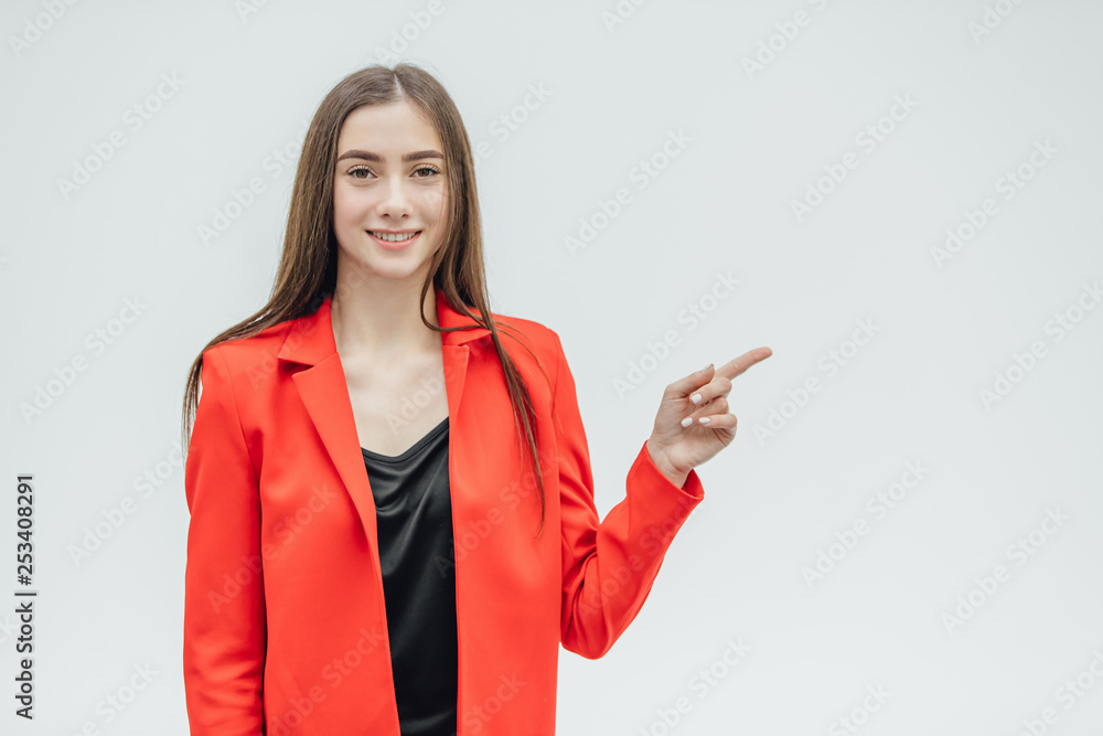 Portrait of a beautiful young brunette. Look into the camera. During this, he lifted one arm upward pointing his finger straight. Dressed in a red jacket.