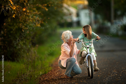Little girl learning to ride her bicycle with the help of her grandmother.