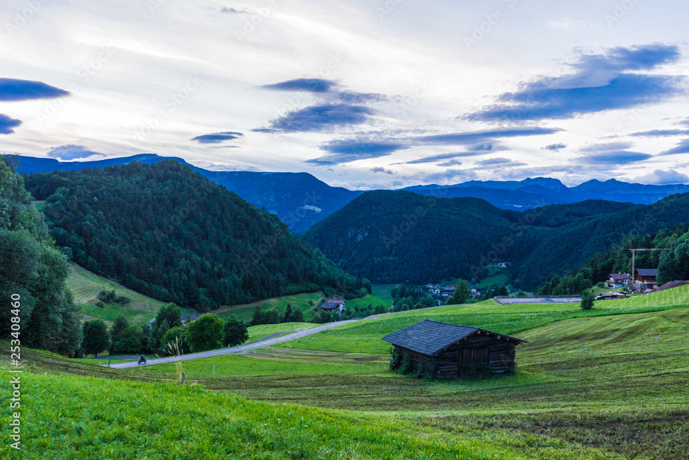 Alpe di Siusi, Seiser Alm with Sassolungo Langkofel Dolomite, a large green field with a mountain in the background Alpe di Siusi, Seiser Alm with Sassolungo Langkofel Dolomite, a large green field with a mountain in the background