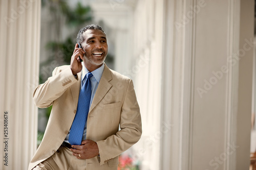 Mid-adult businessman smiling while talking on his cell phone.