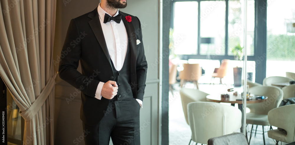 Man in expensive custom tailored suit, tuxedo standing and posing indoors Man in expensive custom tailored suit, tuxedo standing and posing indoors