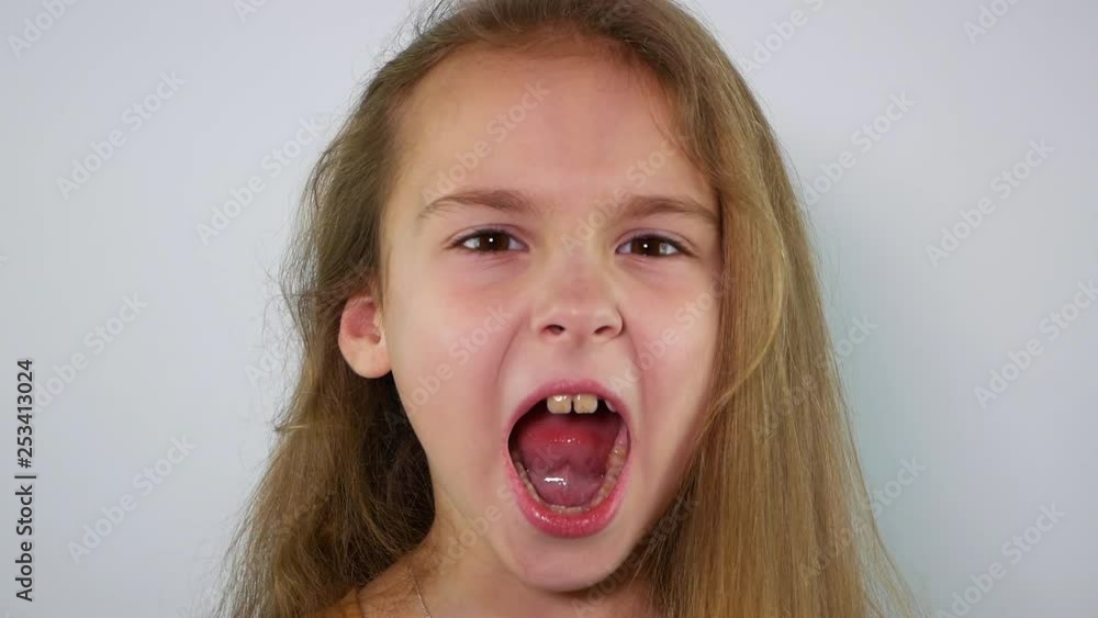 The girl screams with her mouth wide open. The girl screams with her mouth wide open.