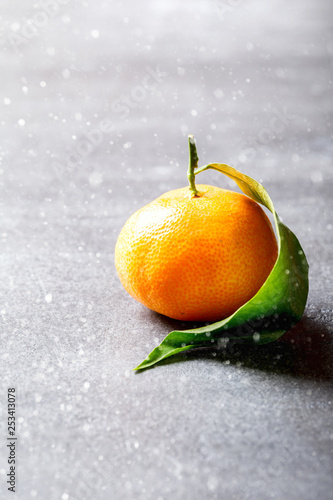 Fresh delicious mandarin, tangerine, clementine with green leaf on gray background. Ripe citrus fruits.Creative minimalistic food concept.Drawn Snowfall. Copy space for Text. © lily_rocha