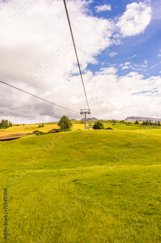 Alpe di Siusi, Seiser Alm with Sassolungo Langkofel Dolomite, a close up of a lush green field with Codrington Wind Farm in the background photo