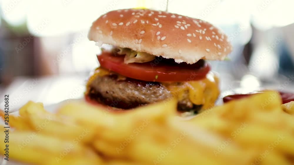 Delicious hamburger with a big chop and a jar of french fries with ketchup Delicious hamburger with a big chop and a jar of french fries with ketchup