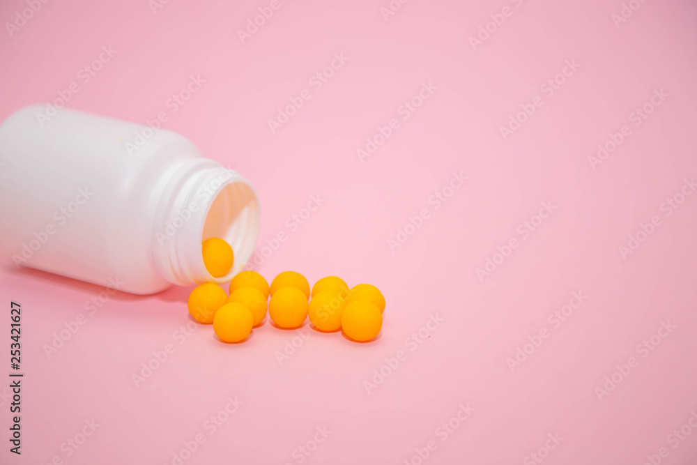 yellow vitamins in a white jar on a pink background. White bank with place for text and tablets. scattered vitamins. dietary supplements, tablets, vitamins, capsules. The concept of a healthy life. yellow vitamins in a white jar on a pink background. White bank with place for text and tablets. scattered vitamins. dietary supplements, tablets, vitamins, capsules. The concept of a healthy life.