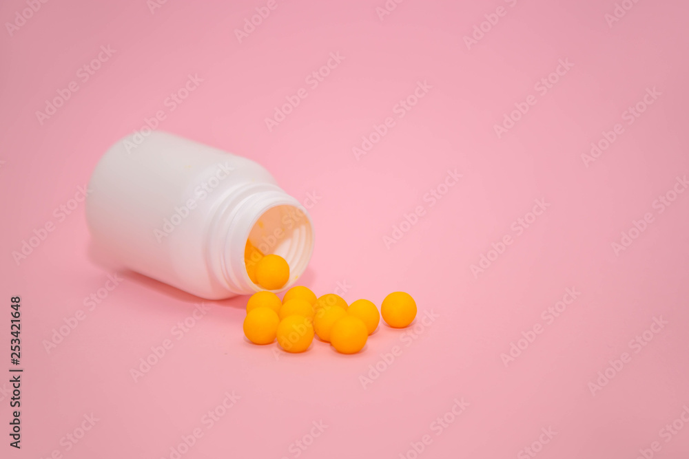 yellow vitamins in a white jar on a pink background. White bank with place for text and tablets. scattered vitamins. dietary supplements, tablets, vitamins, capsules. The concept of a healthy life. yellow vitamins in a white jar on a pink background. White bank with place for text and tablets. scattered vitamins. dietary supplements, tablets, vitamins, capsules. The concept of a healthy life.