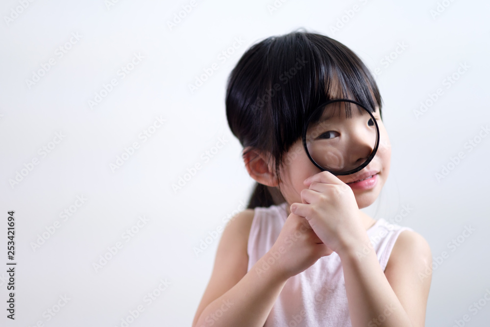Little Asian girl child looking through a magnifying glass isolated on white background Little Asian girl child looking through a magnifying glass isolated on white background
