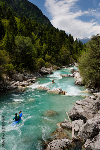 Fototapeta Naklejka Na Ścianę i Meble -  Kayakers shooting the cold emerald green alpine water of the Upper Soca River near Bovec Slovenia with Kanin mountains in the Julian Alps