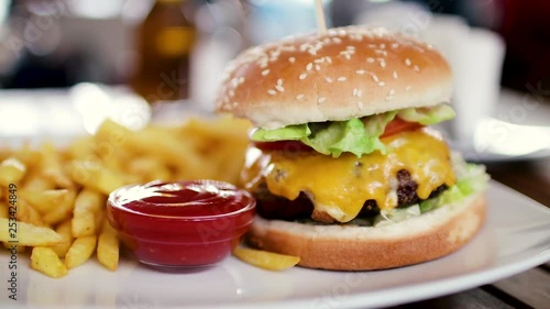 Delicious hamburger with a big chop and a jar of french fries with ketchup