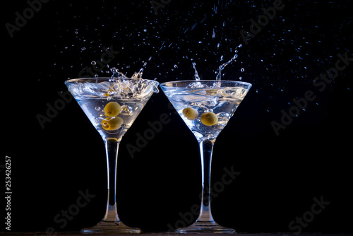 Two martinis with splashing olives