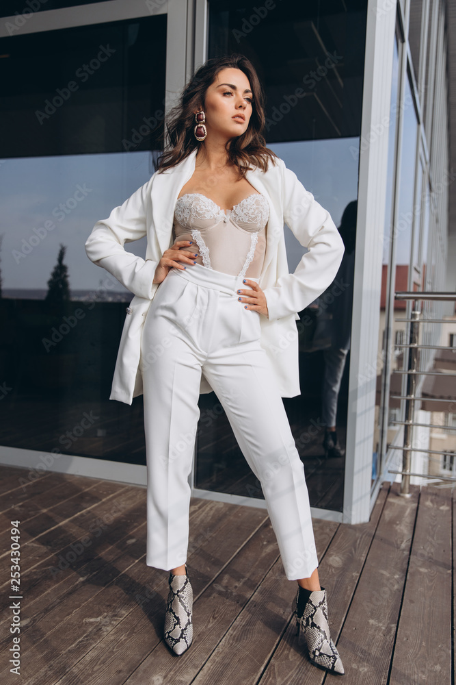 Fotografia do Stock: Beautiful young sexy woman, glamour girl in the white  elegant jacket, corset, suit, makeup pastel tone lipstick, nails on the  office balcony with the urban background.