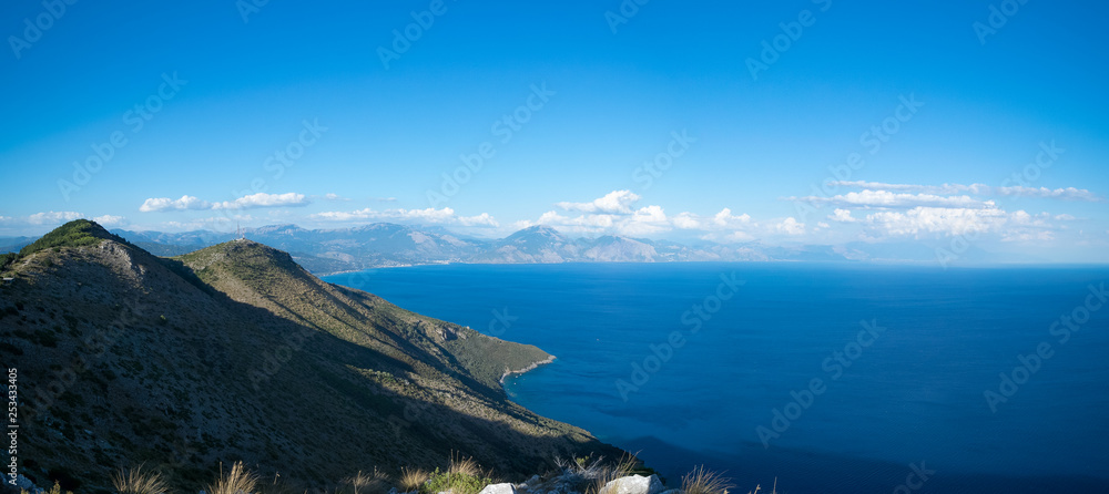 Natural panorama from the top of a mountain to the sea with a big portion of  blue sky and some clouds to the horizon