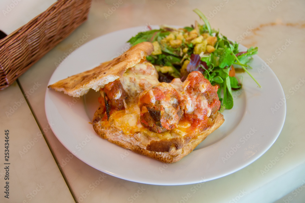 Meat balls on cheese toast with tomato sauce and green salad