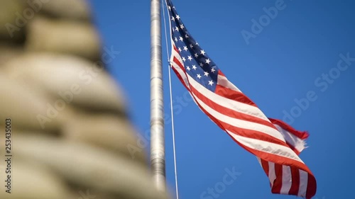 American flag flies majestically on windy day with bright blue sky in background slow motion