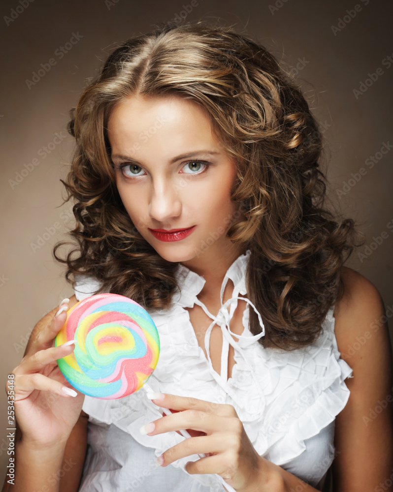  Beauty curly girl portrait holding colorful lollipop.