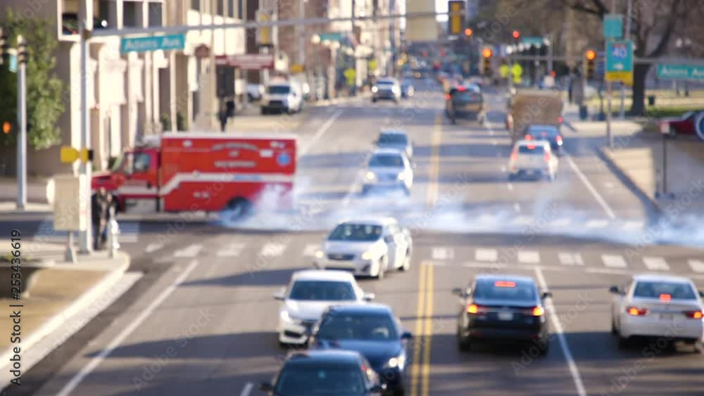 Ambulance drives past with smoke and pollution on busy road downtown Ambulance drives past with smoke and pollution on busy road downtown