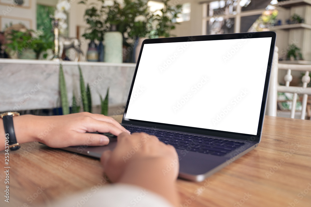 Mockup image of a woman using and typing on laptop with blank white screen on wooden table Mockup image of a woman using and typing on laptop with blank white screen on wooden table