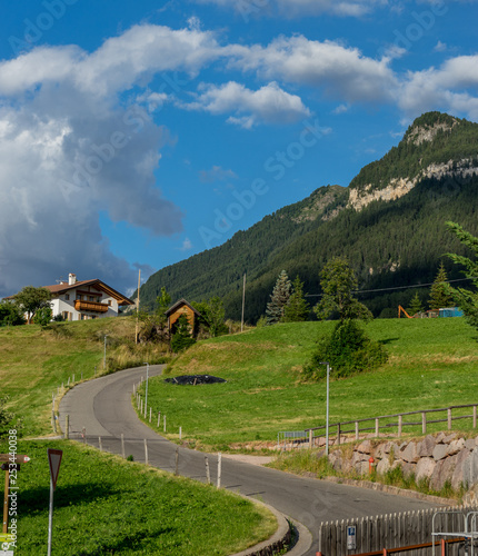 Alpe di Siusi, Seiser Alm with Sassolungo Langkofel Dolomite, a trekking walking winding path in a lush green field