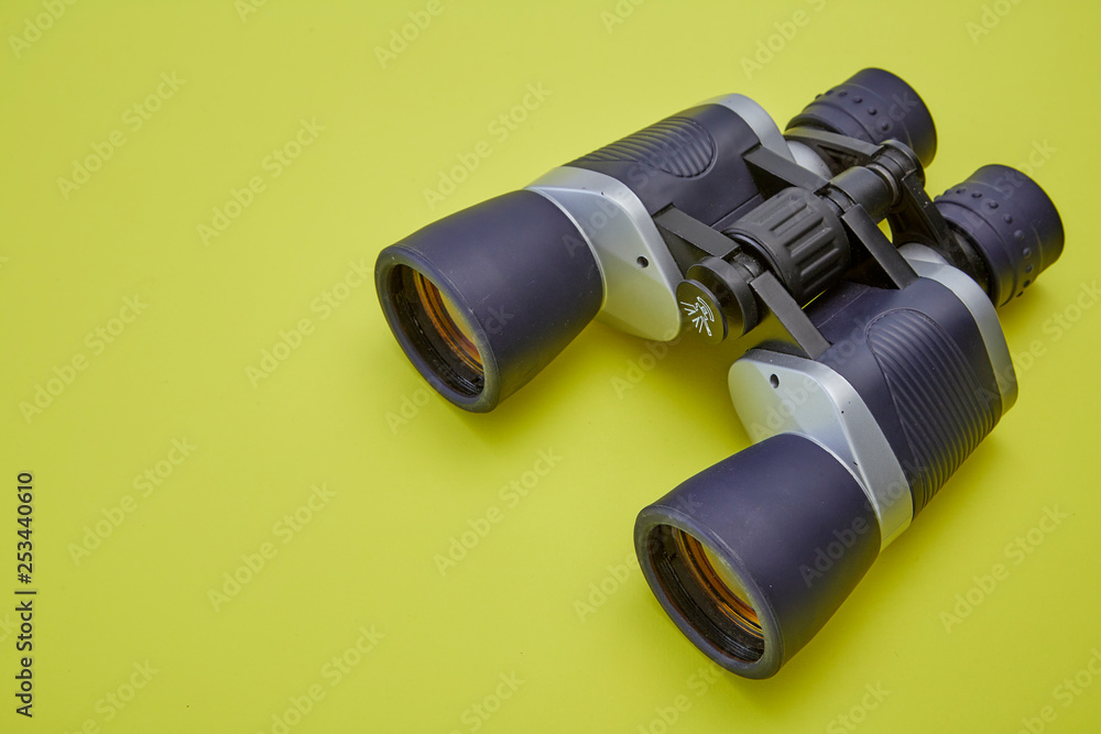 Binoculars silver and gray on yellow background Binoculars silver and gray on yellow background