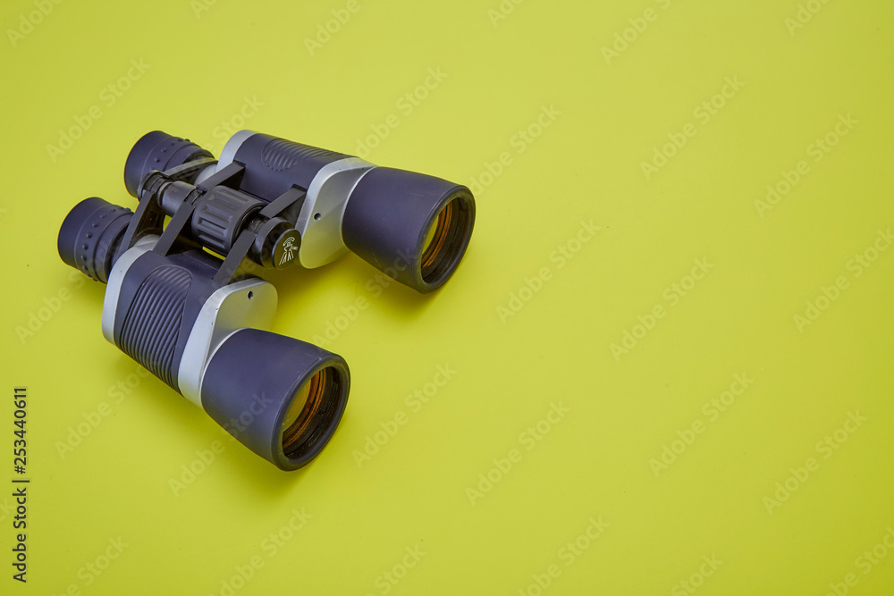 Binoculars silver and gray on yellow background