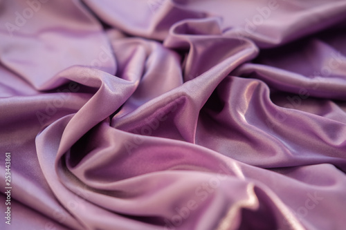 Close up pink fabric. The purple fabric is laid out waves. Fuchsia sateen fabric for background or texture.
