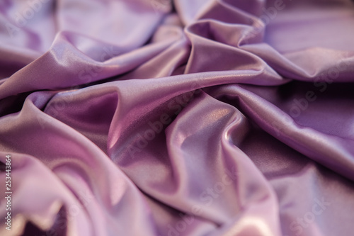 Close up pink fabric. The purple fabric is laid out waves. Fuchsia sateen fabric for background or texture.