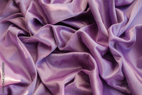 Close up pink fabric. The purple fabric is laid out waves. Fuchsia sateen fabric for background or texture.