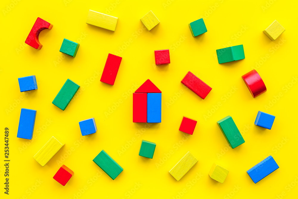 Children background. Wooden building blocks for developing and entertainment on yellow background top view Children background. Wooden building blocks for developing and entertainment on yellow background top view