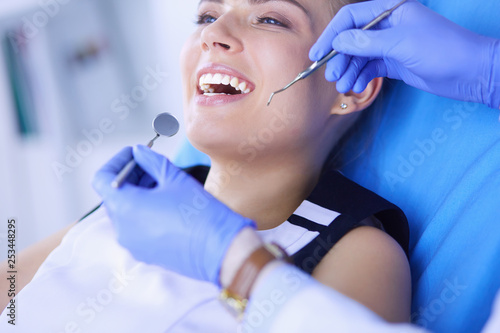 Young Female patient with open mouth examining dental inspection at dentist office.