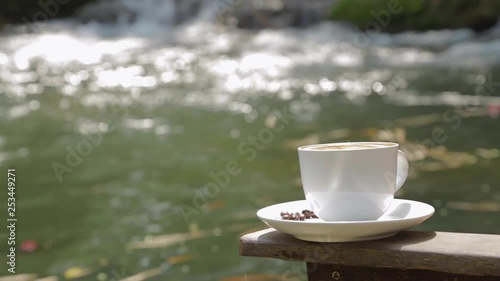 Pan motion effect of a cup of coffee near by the water fall. 