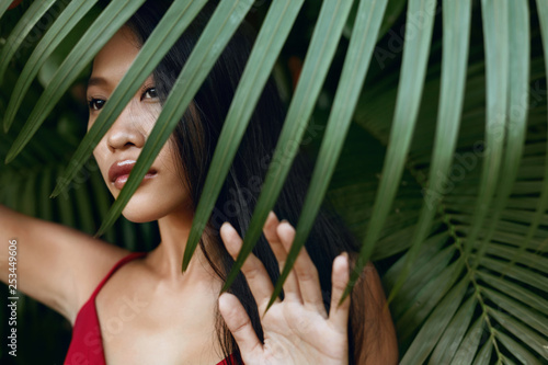 Beauty. Beautiful asian woman with palm leaf over face in nature