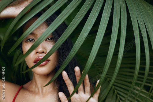 Beauty. Beautiful asian woman with palm leaf over face in nature