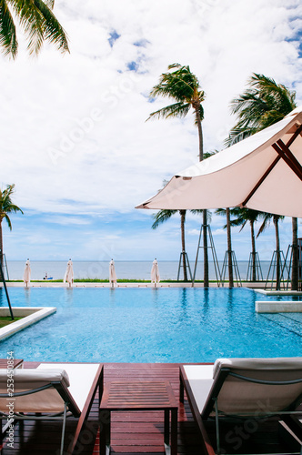 Seaside infinity edge pool with beach bed and umbrella