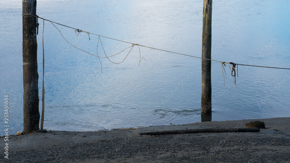 Old wooden pier pillars with rope at low tide Old wooden pier pillars with rope at low tide